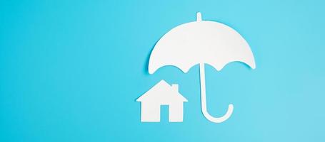 paraply täcka hem papper på blå bakgrund. garanti, underhåll, fastigheter och försäkringskoncept foto