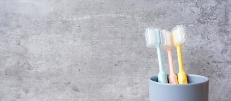 uppsättning tandborstar i kopp på väggbakgrund i badrummet. världens munhälsodag och gratis tanddagkoncept foto
