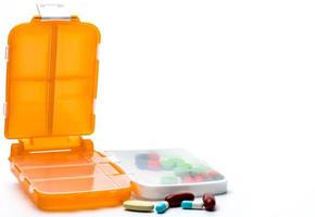 orange piller box med tabletter och kapsel piller isolerad på vit bakgrund med kopia utrymme. förbereda medicin före arbete eller resa utomlands koncept. foto