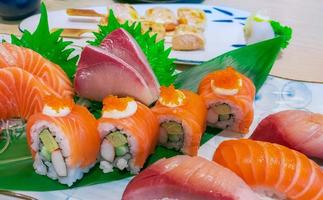 japansk mat combo set på vit platta. lax sushi, sashimi och nigiri på restaurangbordet. fiskkött skivat och japan vinägerade risrullar med skaldjur och grönsaker. hälsosam japansk mat. foto