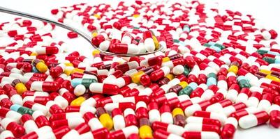 antibiotika kapslar piller i rostfritt stål sked på vit bakgrund med kopia utrymme. läkemedelsresistens koncept. antibiotikadroganvändning med rimligt och globalt hälsokoncept. foto
