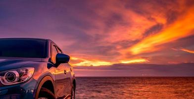 blå kompakt suv-bil med sport och modern design parkerad vid stranden i solnedgången. hybrid- och elbilsteknik. parkeringsplats. bilindustrin. bilvård affärsbakgrund. vacker himmel. foto