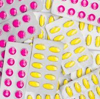ovanifrån av rosa och gula tabletter piller i blisterförpackningar. nsaids kan irriterad mage orsaka magsår. piller mot smärta, mensvärk, huvudvärk och tandvärk. foto
