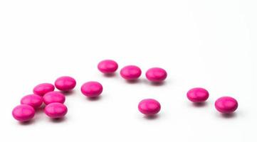 hög med rosa runda sockerdragerade tabletter piller isolerad på vit bakgrund med kopia utrymme. färgglada piller för behandling mot ångest, antidepressiva och migränhuvudvärksprofylax. foto
