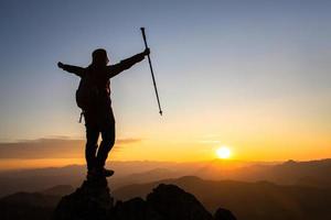 siluett av en kvinna som står på ett berg koncept av ledarskap, framgång, vandring. foto
