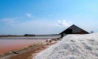 landskap av saltlake salt gård med blå himmel på solig dag. saltlager. hög med ekologiskt havssalt. råvara för saltindustri. natriumkloridmineral. avdunstning av havsvatten. jod. foto