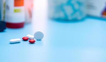 selektivt fokus på runda vita och röda tabletter piller på oskärpa plast drogflaska. apoteksprodukter. läkemedelsindustri. hälsobudget och sjukförsäkringsbakgrund. polyfarmaci. foto