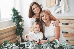 poartrait nära växterna. mamma, mormor och dotter har det bra i köket foto