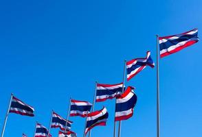 många av thailands flagga vajande på toppen av flaggstången mot blå himmel. thailändska flaggan ritades till toppen av flaggstången. rött, blått och vitt rektangeltyg. nationalflagga för kungariket thailand. foto