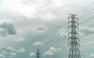 högspänningselektrisk pylon och elektrisk ledning med grå himmel och vita moln. elstolpar. kraft och energi koncept. högspänningsnättorn med trådkabel. infrastruktur. kraftfördelning foto