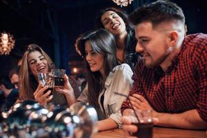 vid barbordet. vackra ungdomar har fest tillsammans med alkohol på nattklubben foto