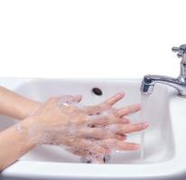 kvinna tvättar handen med tvålskum och kranvatten i badrummet. handrengör under kranen på handfatet för personlig hygien för att förhindra influensa och coronavirus. bra handtvätt för att döda bakterier, virus. foto