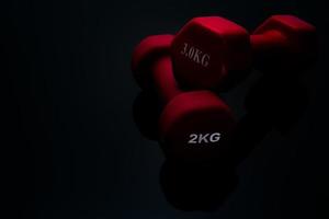 röda och mörkrosa hantlar isolerad på svart bakgrund. 2,3 kg hantlar. styrketräningsutrustning. bodybuilding träningstillbehör. utrustning för träning på gymmet eller hemma. sportutrustning. foto