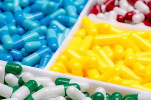 selektivt fokus på grön-vita kapselpiller på suddiga gula, blåa, röda-vita kapselpiller. val av läkemedel för rimlig användning på sjukhus. läkemedelsindustri. läkemedelsverksamhet. apotek foto