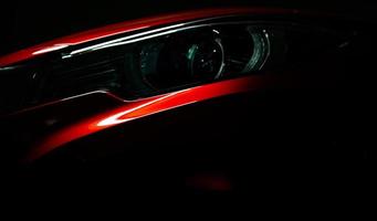 närbild strålkastare av glänsande röd lyx suv kompakt bil. elegant elbilsteknik och affärsidé. hybridbil och bilkoncept. bil parkerad i utställningslokal eller motormässa. bilåterförsäljare. foto