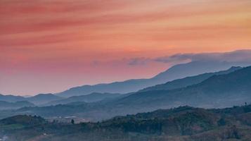 vackert naturlandskap av bergskedja med solnedgångshimmel och moln. lantlig by i bergsdalen i thailand. landskap av bergslager i skymningen. tropisk skog. naturlig bakgrund. foto