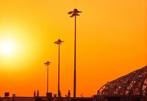 hög elektrisk pylon på flygplatsen vid solnedgången med en orange himmel. strålkastarstolpen på flygfältet. energistöd på flygplatskonceptet. metallstruktur arkitektur. utomhus led lampa lyser stolpar. foto