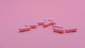 rosa kapslar piller på rosa bakgrund. vitaminer och kosttillskott. onlineapotek. apotek butik banner. läkemedelsindustri. kvinnans sjukförsäkring koncept. piller för kärlek och lyckligt liv. foto