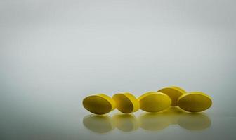 gula ovala tablettpiller med skuggor på vit bakgrund med vackra kreativa mönster och kopieringsutrymme för text. mild till måttlig smärtbehandling. smärtstillande medicin. foto