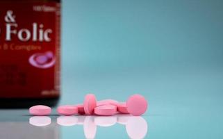 runda rosa tabletter piller på gradient bakgrund. vitaminer och mineraler plus folsyra vitamin e och zink i läkemedelsflaska på gradientbakgrund. rosa tabletter piller för under och efter graviditet kvinna. foto