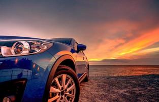 blå kompakt suv-bil med sport och modern design parkerad vid stranden i solnedgången. hybrid- och elbilsteknik. parkeringsplats. bilindustrin. bilvård affärsbakgrund. vacker himmel. foto