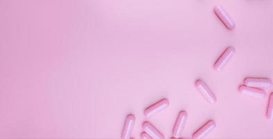 ovanifrån rosa kapslar piller på rosa bakgrund. sjukvård webb banner. vitaminer och kosttillskott för kvinnor koncept. läkemedelsindustri. ämnen för bröstcancer eller kvinnors hälsa. hälsosamt liv. foto