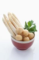 sparris, potatis och persilja i skål på vit bakgrund foto