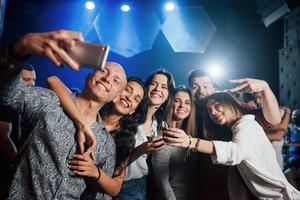 grupp människor. vänner tar selfie i vacker nattklubb. med drinkar i händerna foto