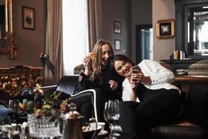 två kvinnliga vänner har trevligt i vacker lyxig modern restaurang foto