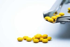 makro shot detalj av gula runda sockerdragerade tabletter piller på rostfritt stål läkemedelsbricka och några av dem är på vit bakgrund foto