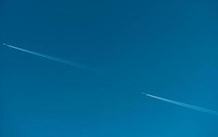 två flygplan med vita kondensspår. jetplan på klarblå himmel med ångspår. resa med flygplan koncept. spår av avgaser från flygplansmotorn. flygplan med vita ränder. foto