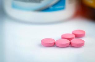 runda rosa tabletter piller på suddig drogflaska. vitaminer och mineraler plus folsyra vitamin e och zink i läkemedelsflaska på gradientbakgrund. rosa tabletter piller för under och efter graviditet kvinna. foto