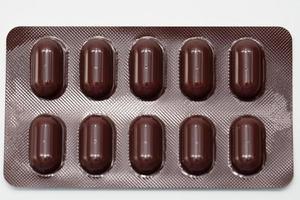 tabletter piller i brun blisterförpackning. läkemedelsindustri. läkemedelsförpackning för att skydda mot ljus. apoteksprodukter. närbild tabletter piller i förpackning på vit bakgrund. sjukvård koncept. foto