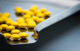 makro skott detalj av gula runda socker belagda tabletter piller på rostfritt stål drog fack foto