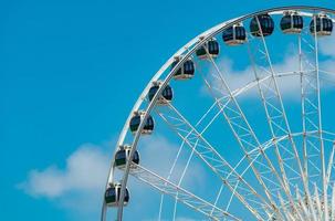 närbild modernt pariserhjul mot blå himmel och vita moln. pariserhjul på tivoli för underhållning och rekreation på semestern. modern konstruktion av pariserhjul i nöjen. rolig festival. foto