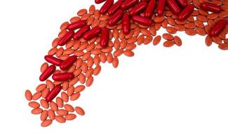 hög med bruna tabletter och röda kapselpiller på vit bakgrund. järntabletter piller för behandling av anemi. vitaminer och kosttillskott koncept. läkemedelsindustri. apoteksprodukter för anemi. foto