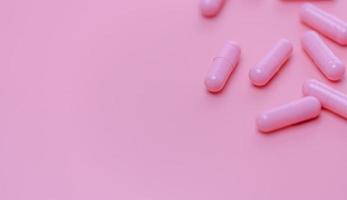 rosa kapslar piller på rosa bakgrund. vitaminer och kosttillskott. onlineapotek. apotek butik banner. läkemedelsindustri. kvinnans sjukförsäkring koncept. piller för kärlek och lyckligt liv. foto