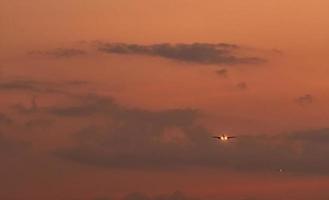 kommersiellt flygbolag. passagerarplan som landar på flygplatsen med vacker solnedgångshimmel och moln. ankommande flyg. flygplan som flyger i en linje för landning. flygplan öppet ljus på kvällsflyget. foto