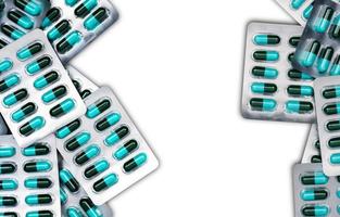 ovanifrån av blå och gröna antibiotika kapsel piller i blisterförpackningar isolerad på vit bakgrund med kopia utrymme. antimikrobiell läkemedelsresistens och antibiotikaläkemedelsanvändning med rimligt koncept. foto