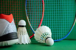 badminton sportutrustning på det gröna golvet av badmintonbanan fjäderbollar, racketar, skor, selektivt fokus på fjäderbollar, badmintonidrottsälskare runt om i världen koncept. foto