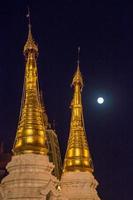 spets av två pagoder på fullmåne i yangon foto