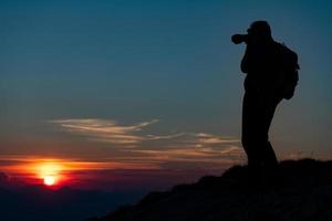 fotografera solnedgången i bergen. fotograf i siluett foto