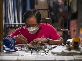 chiang mai, thailand, 2021 - asiatisk urmakare med fokus på sitt arbete foto