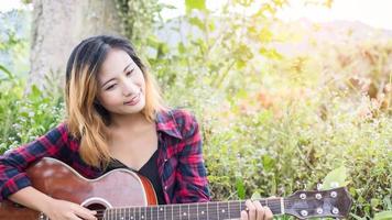 ung kvinnas hand spelar gitarr. utomhus foto