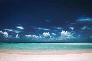 sandstrand, klart genomskinligt hav och blå himmel. foto