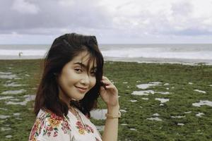 en ung asiatisk flicka på stranden ler mot kameran i gunungkidul, indonesien foto