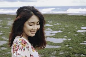 en ung asiatisk flicka på stranden ler mot kameran i gunungkidul, indonesien foto