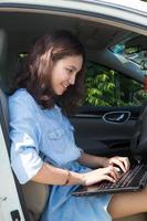 asiatisk kvinna med en bärbar dator i sin bil foto