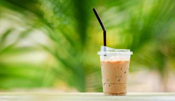 iskaffe i högt glas, isbitar. sval sommardrink med sugrör på varm naturlig grön oskärpa bakgrund. kopieringsutrymme foto