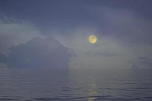 ett fantasy sagolandskap med månen ovanför vattenytan. foto